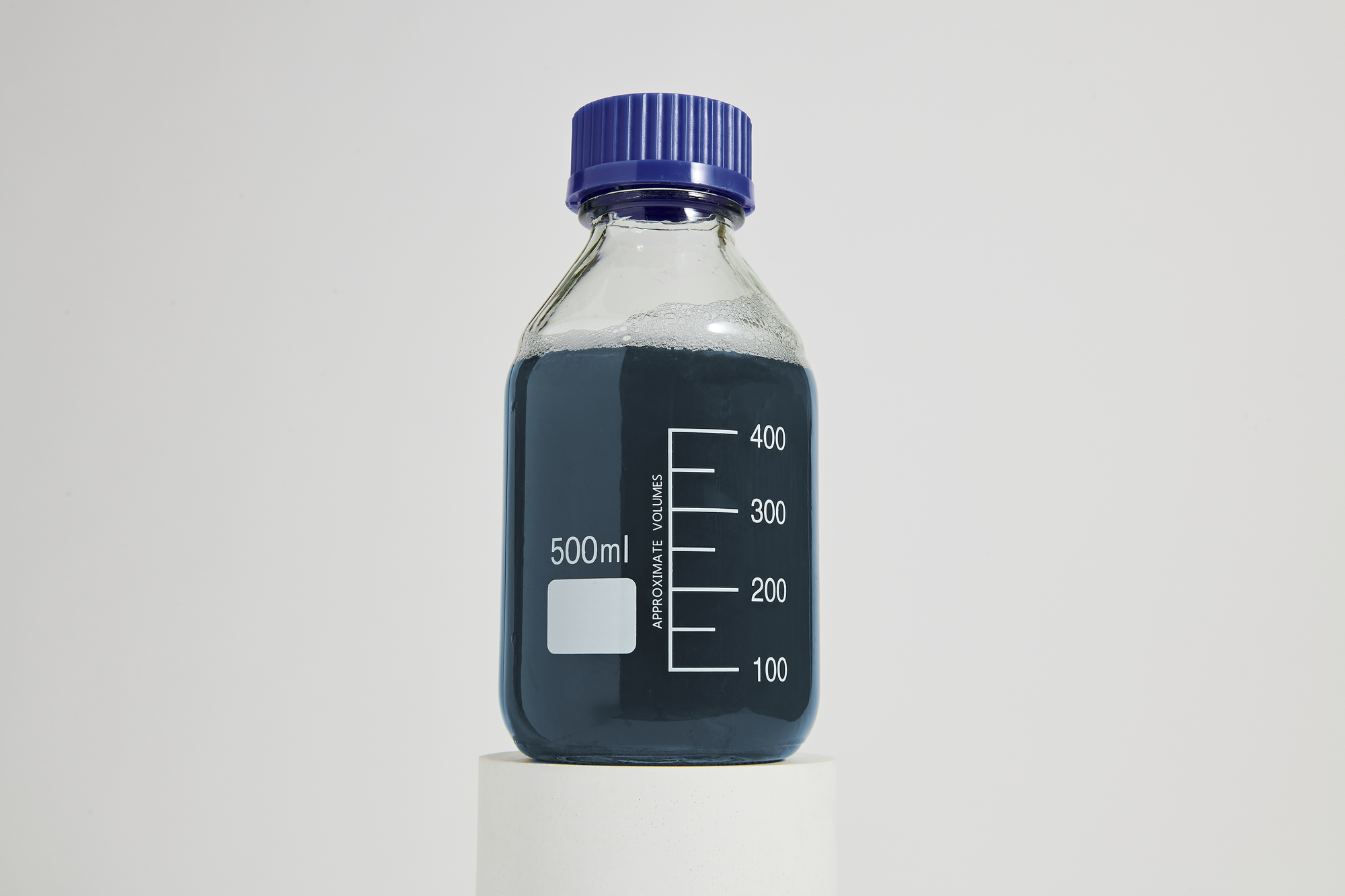 Clear lab bottle with blue liquid on a pedestal